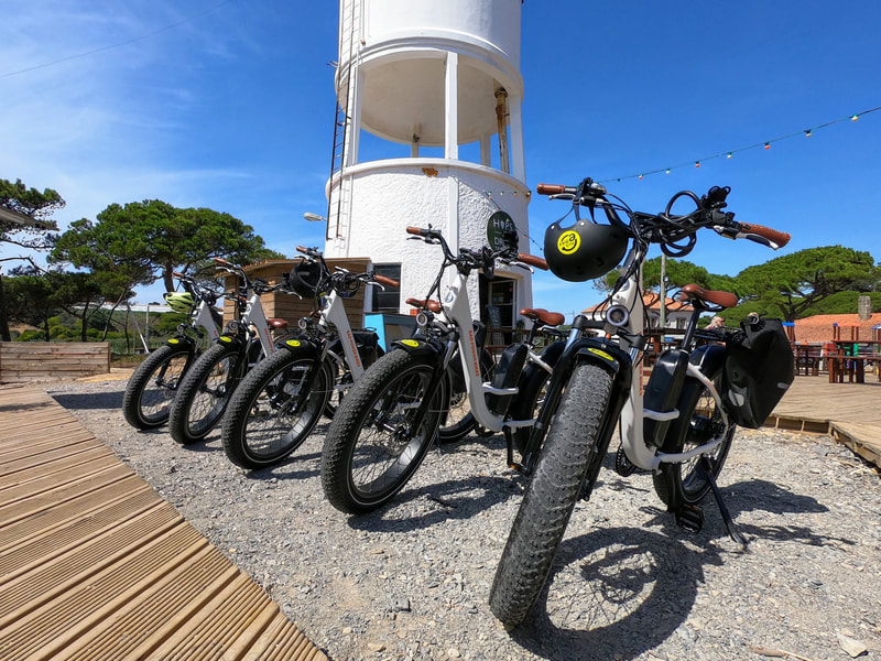 Ebikes de pneus gordos estacionados junto a uma torre de água perto do oceano Atlântico em Sintra