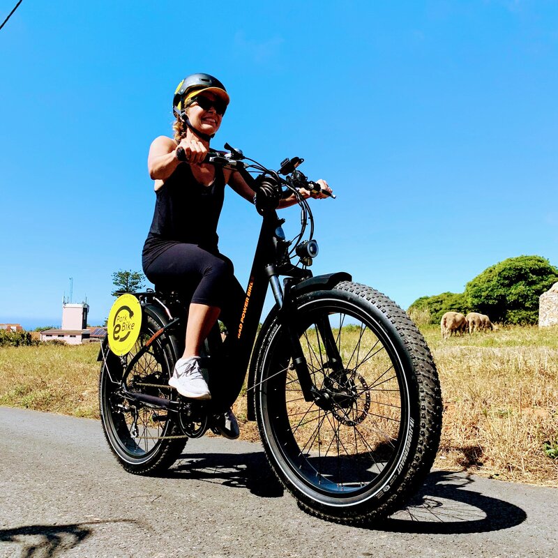 Senhora a pedalar uma moto de pneu gordo ao longo de uma estrada rural